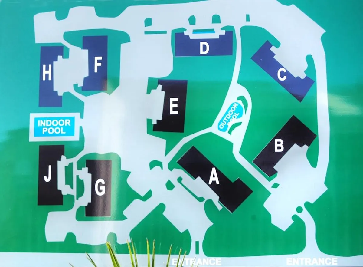 A bright and organized indoor pool area marked by building letters, offering a welcoming spot for swimming and socializing. The entrance and common spaces are visible, indicating accessibility for groups.