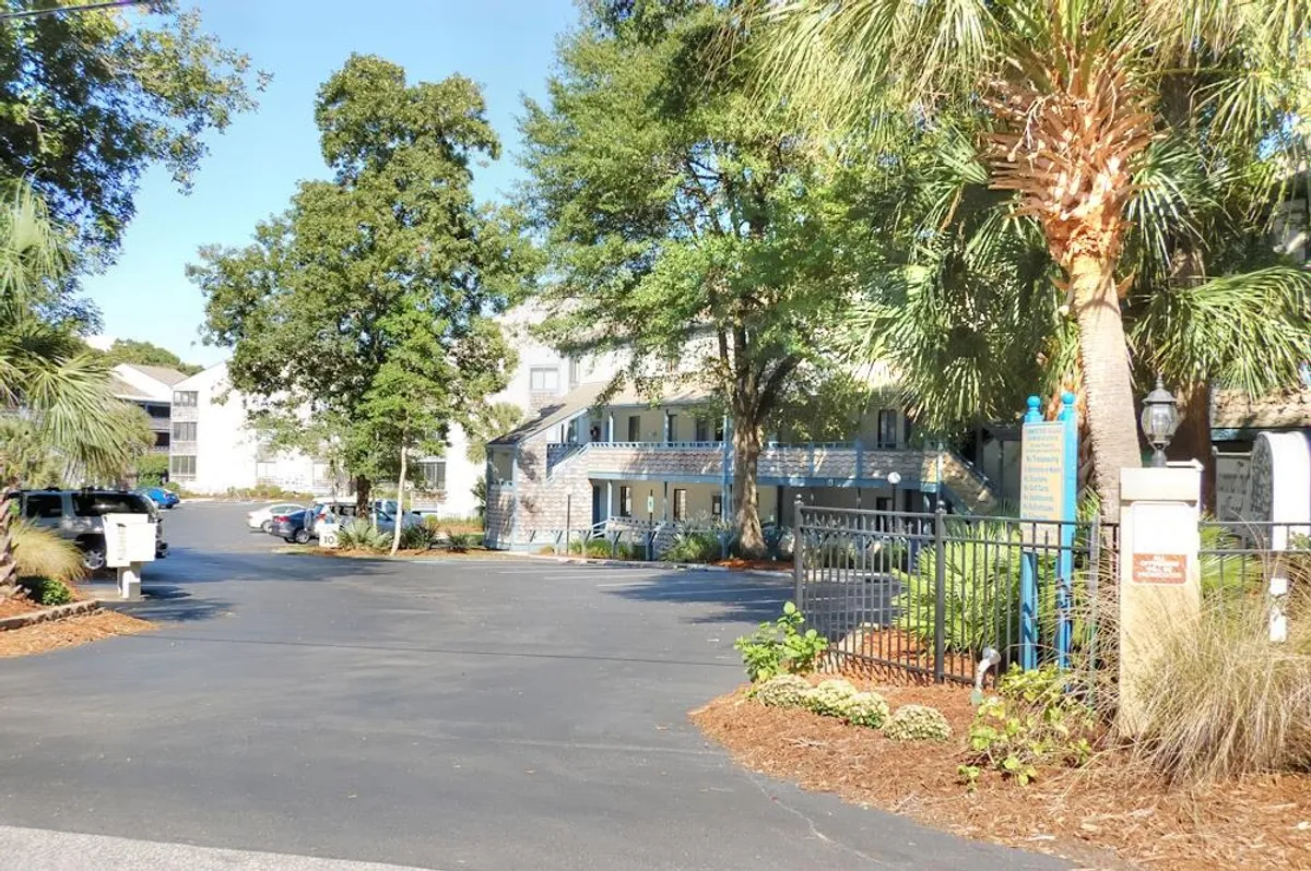 This image captures the inviting entrance to Summertree Village, featuring palm trees, a walkway leading to the building, and a welcoming green space. The scene evokes a sense of arrival, highlighting the community-oriented environment and convenient access for residents and guests.