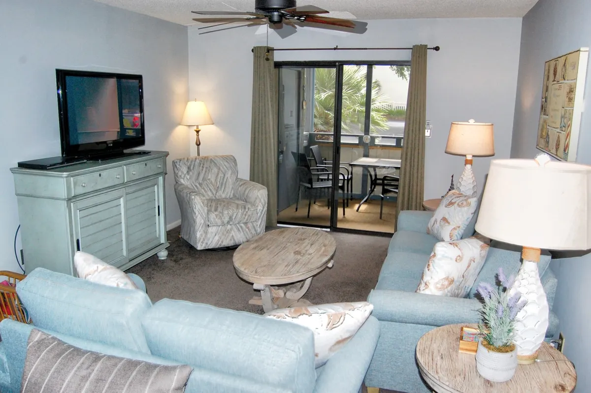 A comfortable living area featuring a sofa, coffee table, TV, and sliding glass door, with the kitchen likely adjacent. This setup visually supports the open-concept layout described, where the kitchen remains connected to the living space for easy conversation and family interaction.