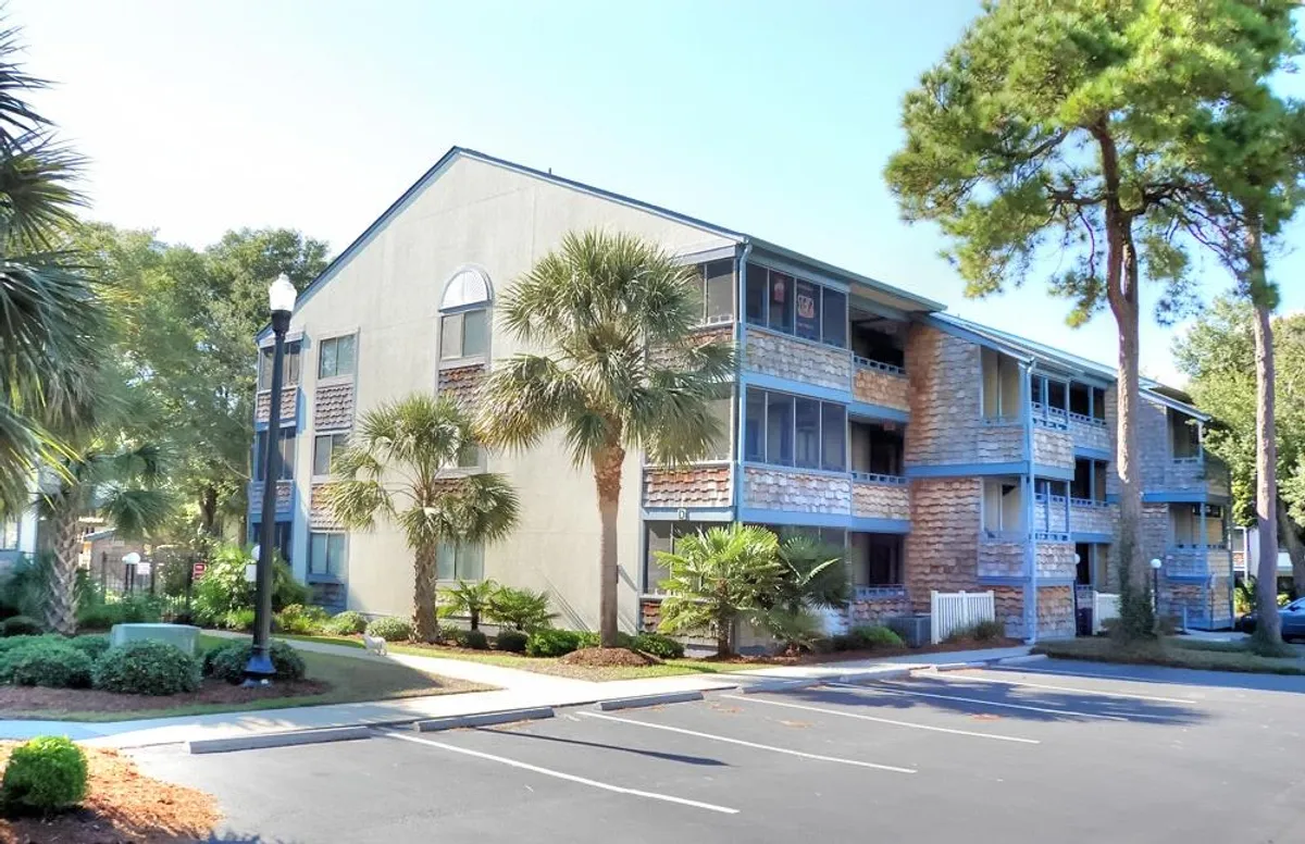 An exterior view of the property featuring multiple balconies, palm trees, and a welcoming landscape. The visible balconies suggest private outdoor spaces perfect for soaking up the sun, enjoying ocean breezes, and connecting with the environment.